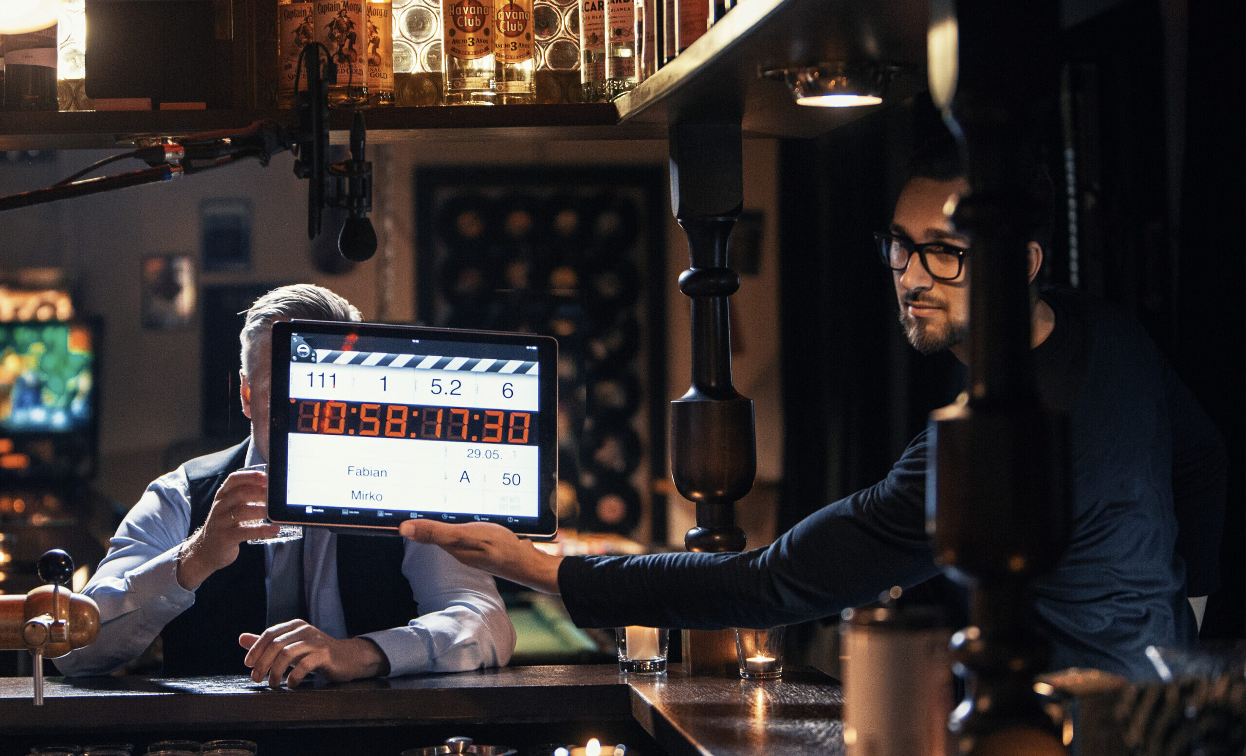Filmset in Bar mit Klappe und Crewmitglied.