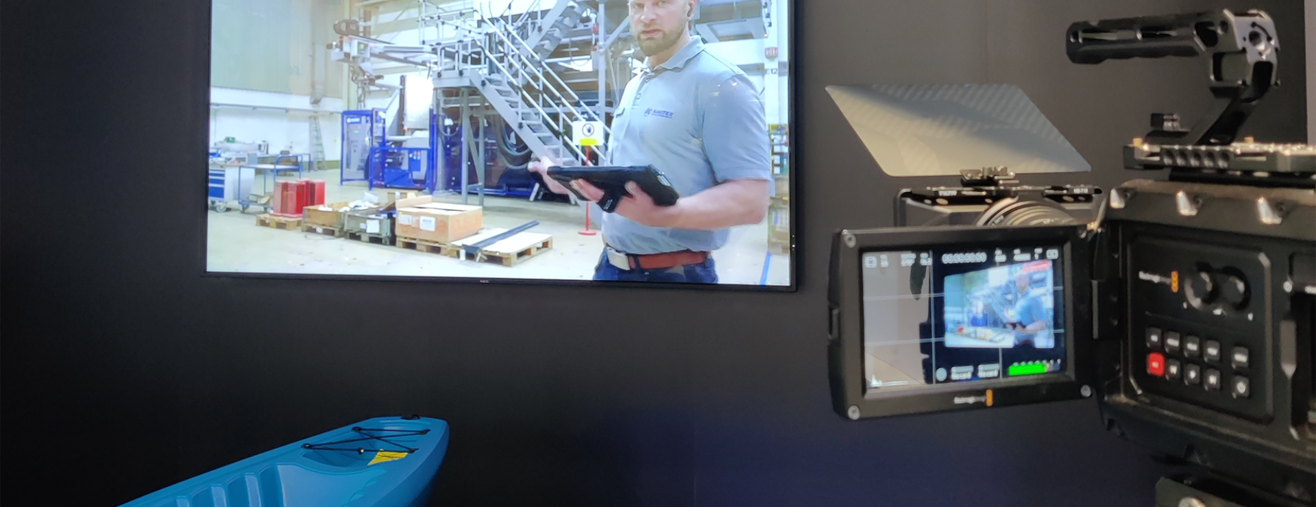 Kamera filmt Bildschirm mit Industrieszene und blauem Kajak.